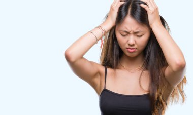 Genç Asyalı kadın çaresiz ve stresli baş ağrısı acı izole arka plan üzerinde 