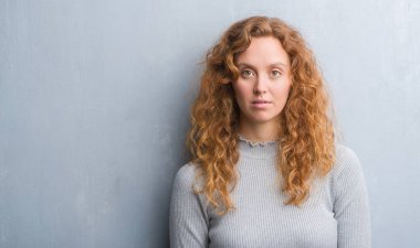 Gri grunge duvar acımak yüz ciddi düşünüyorum üstünde kendine güvenen bir ifade ile genç Kızıl saçlı kadın