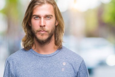 Yüzünde ciddi bir ifade ile izole arka plan üzerinde uzun saçlı Genç yakışıklı adam. Basit ve doğal kameraya bakıyor.