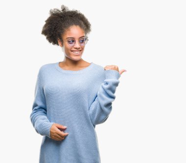 Seyir ve başparmak yanında yukarıyı mutlu yüz ile gülümseyen izole arka plan üzerinde gözlük takan genç afro Amerikalı kadın.