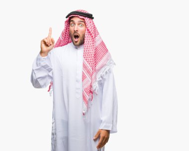 Başarılı fikirle izole arka plan işaret parmağı üzerinde keffiyeh giyen genç yakışıklı adam. Çıktıktan ve mutlu. Bir numara.
