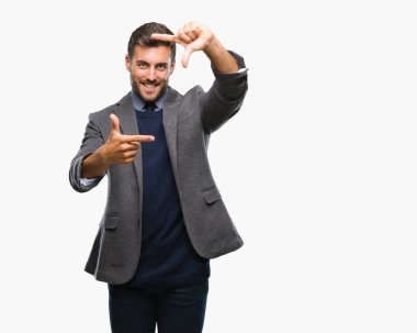 Genç yakışıklı iş adamı elle yapma çerçeve ve parmakları ile mutlu yüz gülümseyen izole arka plan üzerinde. Yaratıcılık ve Fotoğrafçılık kavramı.