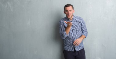 Beyaz delikanlı bir öpücük el ile güzel ve seksi olmak hava üfleme kamera bakarak gri grunge duvarın üzerinden. Aşk ifade.