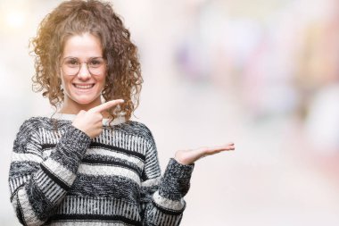 Güzel esmer kıvırcık saçlı Genç kız gözlüklü üzerinden hayran ve el ile sunulması ve parmak ile işaret ederken kameraya gülümseyen izole arka plan.