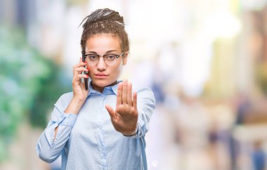Genç örgülü saç Afro-Amerikan iş kız gösteren arama açık eliyle dur işareti ile ciddi ve kendine güvenen ifade, savunma jest yapıyor izole arka plan üzerinde smartphone kullanarak
