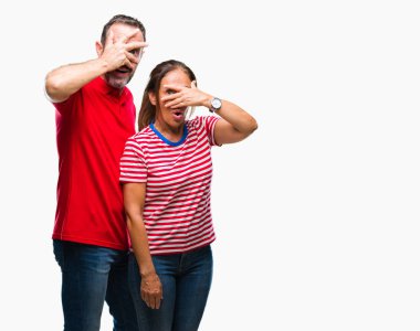 Orta yaş İspanyol çift yüz ve el parmakları utanç ifadesi ile üzerinden baktığımda, gözleriyle kapsayan şok bakmak izole arka plan üzerinde aşık.