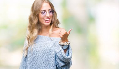 Güzel genç sarışın kadın arıyorum ve başparmak yanında yukarıyı mutlu yüz ile gülümseyen izole arka plan üzerinde güneş gözlüğü takıyor.