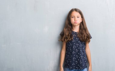 Komik surat ile yanakları şişirme grunge gri duvar genç İspanyol çocuk. Ağız ile hava, deli ifade şişirilmiş.