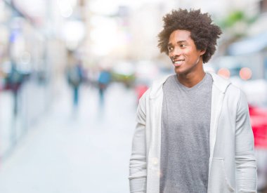 Afro Amerikalı adam uzak tarafına yüzünde, doğal ifade gülümseme ile seyir izole arka plan üzerinde kazak giyiyor. Kendine güvenen gülüyor.