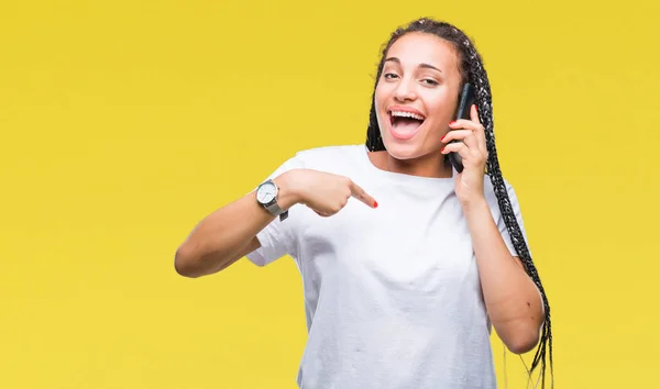 年轻的编织头发非洲裔美国女孩显示打电话使用智能手机在孤立的背景与惊喜的脸指向自己 — 图库照片