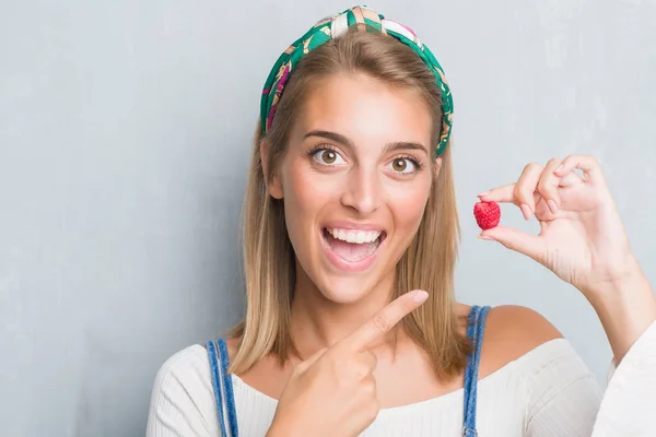 手や指で新鮮なラズベリー非常に幸せのポイントを食べるグランジ灰色の壁に美しい若い女性 — ストック写真