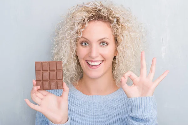 Junge Blonde Frau Über Grunge Grey Wall Eating Chocolate Bar — Stockfoto