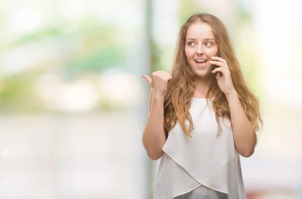 Young Blonde Woman Using Smartphone Pointing Showing Thumb Side Happy — Stock Photo, Image