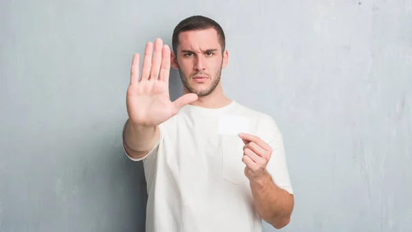 Joven Hombre Caucásico Sobre Pared Gris Grunge Mostrando Tarjeta Visita —  Fotos de Stock