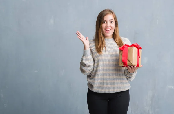 Joven Mujer Adulta Sobre Pared Grunge Gris Sosteniendo Regalo Muy —  Fotos de Stock