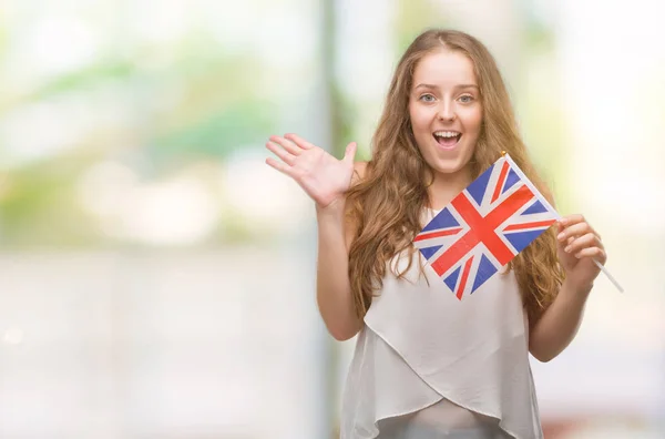大きな悲鳴を上げる勝利を祝って英国非常に幸せと興奮 受賞式の若いブロンドの女性保持フラグ笑顔し 手を上げた — ストック写真