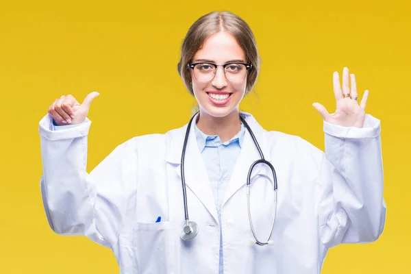 美丽的年轻金发碧眼的医生妇女穿着医疗制服在孤立的背景显示和手指第六 而微笑着自信和快乐 — 图库照片