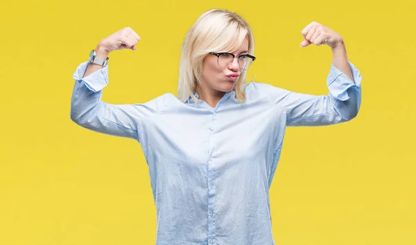 Young beautiful blonde business woman wearing glasses over isolated background showing arms muscles smiling proud. Fitness concept.