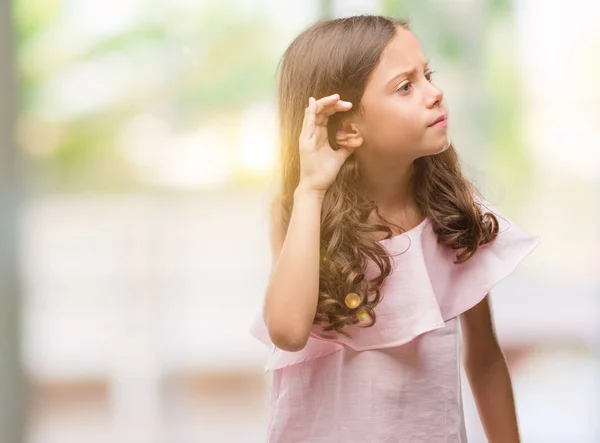 穿着粉红色连衣裙的黑发西班牙裔女孩 用手在耳边听着谣言或流言蜚语 耳聋概念 — 图库照片