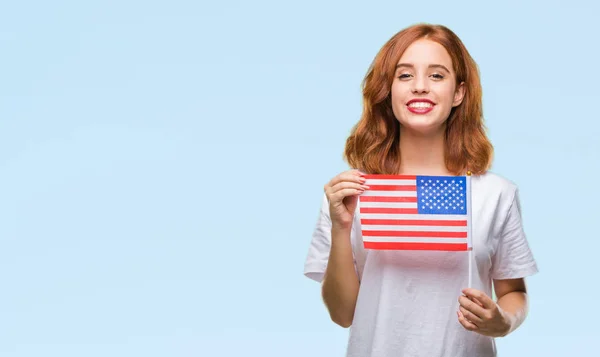 立っていると自信を持って歯を見せて笑顔で笑っている幸せそうな顔で孤立した背景にアメリカの国旗を保持している若い美しい女性 — ストック写真