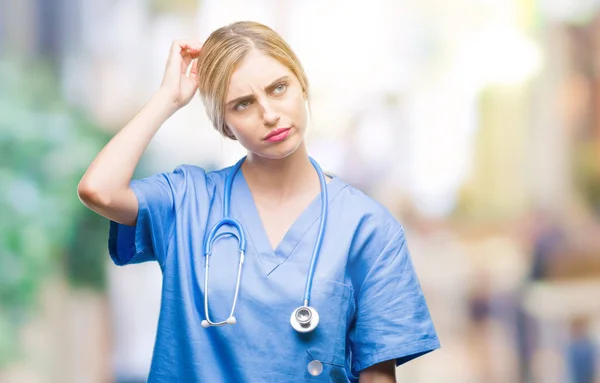 年轻美丽的金发医生外科护士妇女在孤立的背景混淆和疑惑的问题 疑惑不定 用手在头上思考 沉思概念 — 图库照片