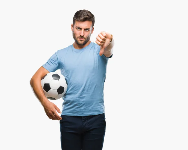 年轻英俊的男子举行足球足球在孤立的背景与愤怒的脸 消极的迹象显示不喜欢拇指向下 拒绝概念 — 图库照片