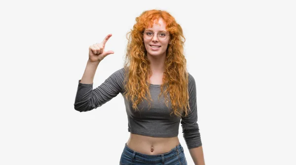 赤毛の若い女性の笑顔と自信を持ってカメラを見ながら指でサイズ記号をやって手でジェスチャーします 測定概念 — ストック写真