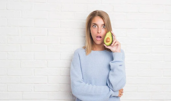 Beautiful Young Woman White Brick Wall Eating Fresh Avocado Scared — Stock Photo, Image