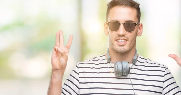 Przystojny Młody Mężczyzna Noszenie Słuchawek Wyświetlono Skierowaną Górę Palcami Liczba — Zdjęcie stockowe
