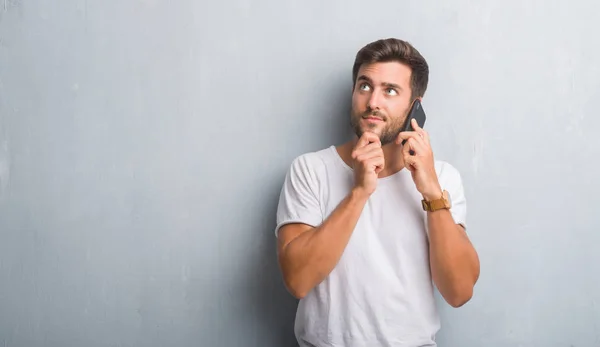 Bel Giovanotto Sul Muro Grigio Grunge Parlando Telefono Faccia Seria — Foto Stock