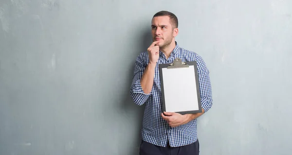 Joven Caucásico Hombre Sobre Gris Grunge Pared Celebración Portapapeles Seria — Foto de Stock