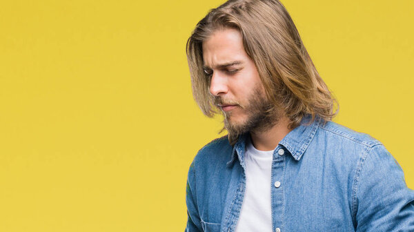 Молодой красивый мужчина с длинными волосами на изолированном фоне с рукой на животе, потому что тошнота, болезненное заболевание чувствует себя нездоровым. Концепция Ache
.