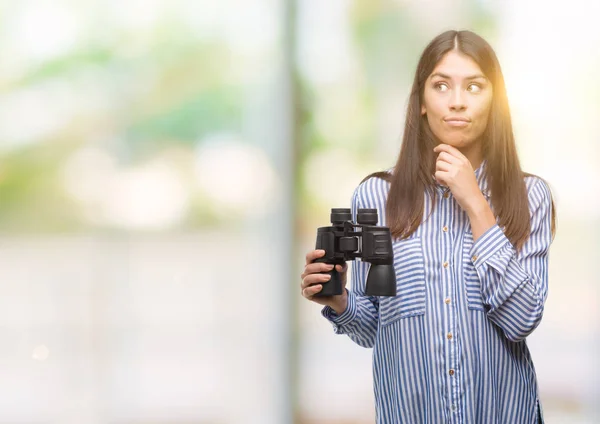 Young Hispanic Woman Holding Binoculars Serious Face Thinking Question Very — Stock Photo, Image