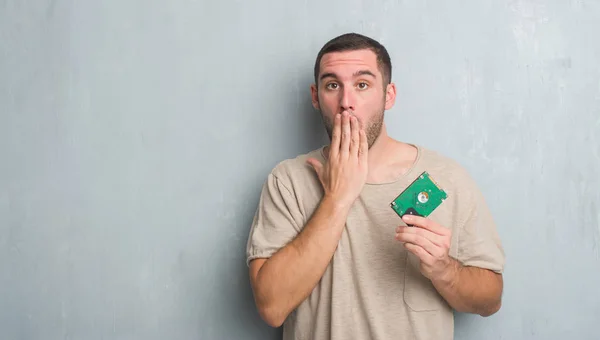 Joven Hombre Caucásico Sobre Pared Grunge Gris Sosteniendo Boca Cubierta — Foto de Stock