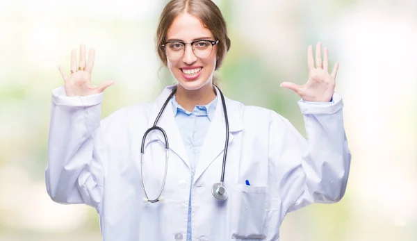美丽的年轻金发碧眼的医生妇女穿着医疗制服在孤立的背景显示和手指排名数字十 而微笑着自信和快乐 — 图库照片