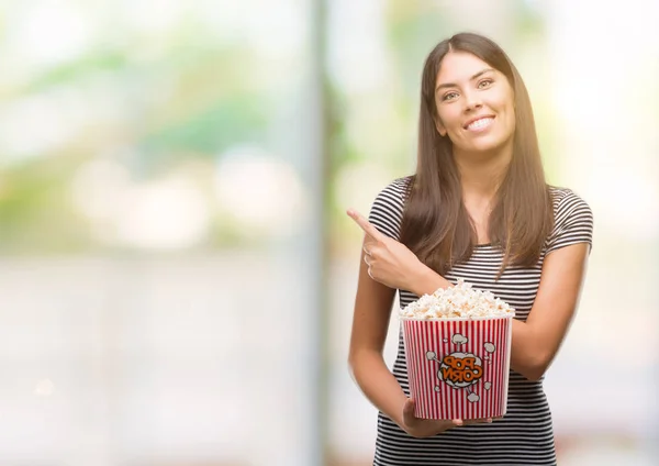 Jovem Bela Hispânica Comer Pipocas Muito Feliz Apontando Com Mão — Fotografia de Stock