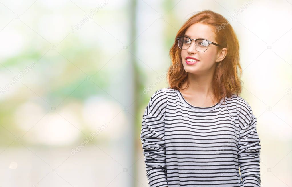 Young beautiful woman over isolated background wearing glasses looking away to side with smile on face, natural expression. Laughing confident.