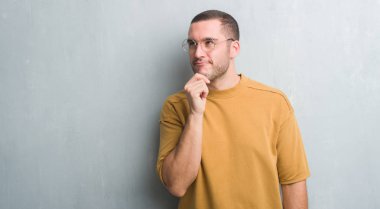 Gri grunge duvar ciddi bir yüz düşünme hakkında soru, çok karışık fikir genç beyaz adam