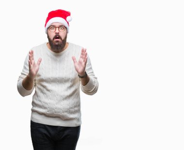 Beyaz delikanlı korkuyor ve şok sürpriz ifade, korku ve heyecan yüz ile izole arka plan üzerinde Noel şapka ve gözlük takıyor.