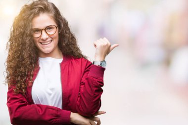 Ceket ve gözlük arıyorum ve başparmak yanında yukarıyı mutlu yüz ile gülümseyen izole arka plan üzerinde giyen güzel esmer kıvırcık saçlı Genç kız.