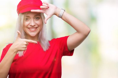 Elle yapma çerçeve ve parmakları ile mutlu yüz gülümseyen izole arka plan üzerinde kırmızı şapkalı sarışın genç kadın. Yaratıcılık ve Fotoğrafçılık kavramı.