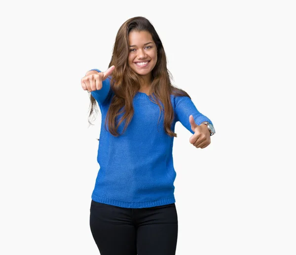 年轻美丽的黑发女人穿着蓝色毛衣在孤立的背景 赞同做积极的手势与手 竖起大拇指微笑 并为成功高兴 看着镜头 赢家的手势 — 图库照片