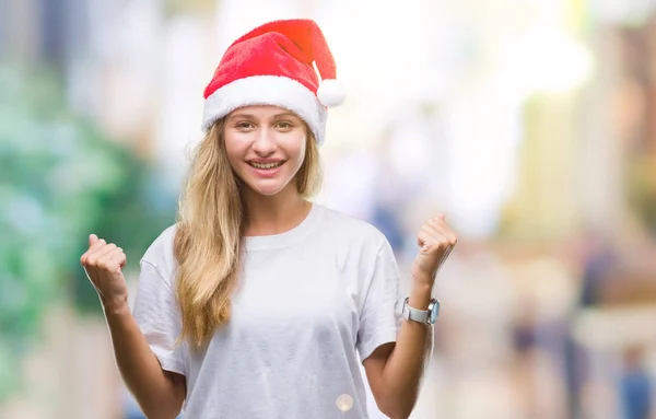 上孤立した背景を祝うクリスマスの帽子をかぶって若い美しいブロンドの女性驚いて腕を上げると成功のため驚くし 目を開きます 勝者の概念 — ストック写真