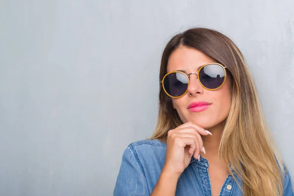 Junge Erwachsene Frau Über Grunge Grauer Wand Mit Retro Sonnenbrille — Stockfoto