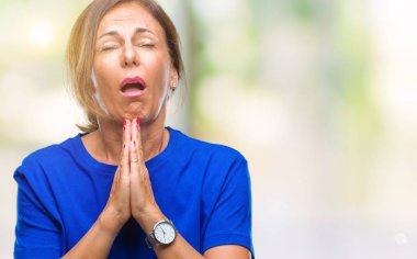 Orta yaş İspanyol kadın kıdemli yalvarıyor ve umut ifade yüzünde çok duygusal ve endişe ile birlikte elleriyle dua izole arka plan üzerinde. Bağışlanmak. Din kavramı.