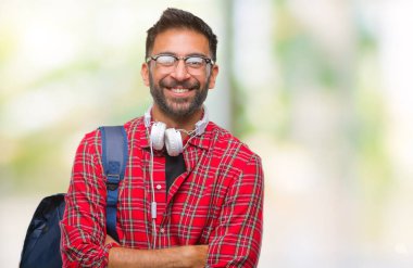 Üzerinde kulaklık ve sırt çantası giyiyor yetişkin İspanyol öğrenci adam mutlu yüz ile gülümseyerek kameraya seyir silah geçti arka plan izole. Olumlu bir kişi.