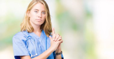 El hareketi ile sembolik silah tutan, çekim silah, kızgın yüz öldürme oynarken arka plan üzerinde tıbbi üniforma giyen güzel genç doktor kadın izole