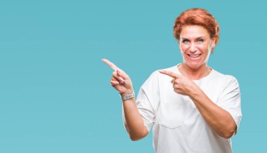 Atrractive üst düzey beyaz Kızıl saçlı kadın gülümseyerek ve iki elleri ve parmakları ile tarafına işaret kamera bakarak izole arka plan.