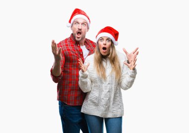 Üzerinde Noel şapka aşık genç çift çılgın kutlama arka plan izole ve başarı için kaldırdı kollarını açarak hayrete ve heyecanlı çığlık gözleri açık. Kazanan kavramı