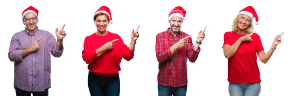 在孤立的背景上戴着圣诞帽的中年人和老年人的拼贴画微笑着看着镜头 用两只手和手指指着一边 — 图库照片